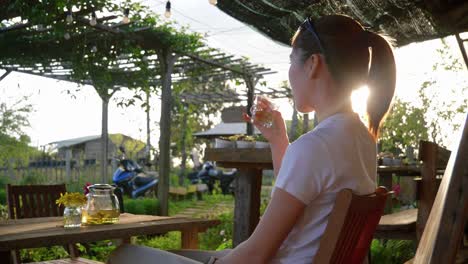 asian female casually drinking from a glass while sitting outside, over shoulder view, vietnam