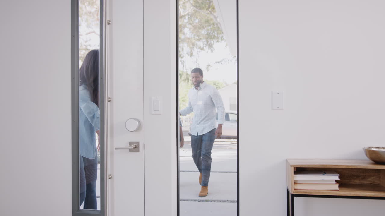 los padres que traen a sus hijos emocionados a casa de la escuela abren la puerta principal de la casa.