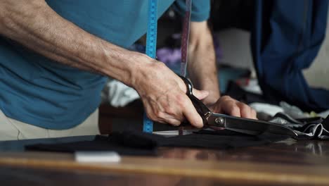 a tailor cuts fabric with scissors