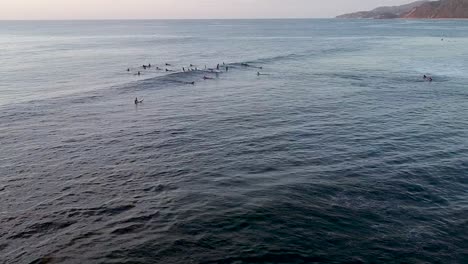 surfers at sunset waiting for the perfect wave to catch in sayulita, mexico