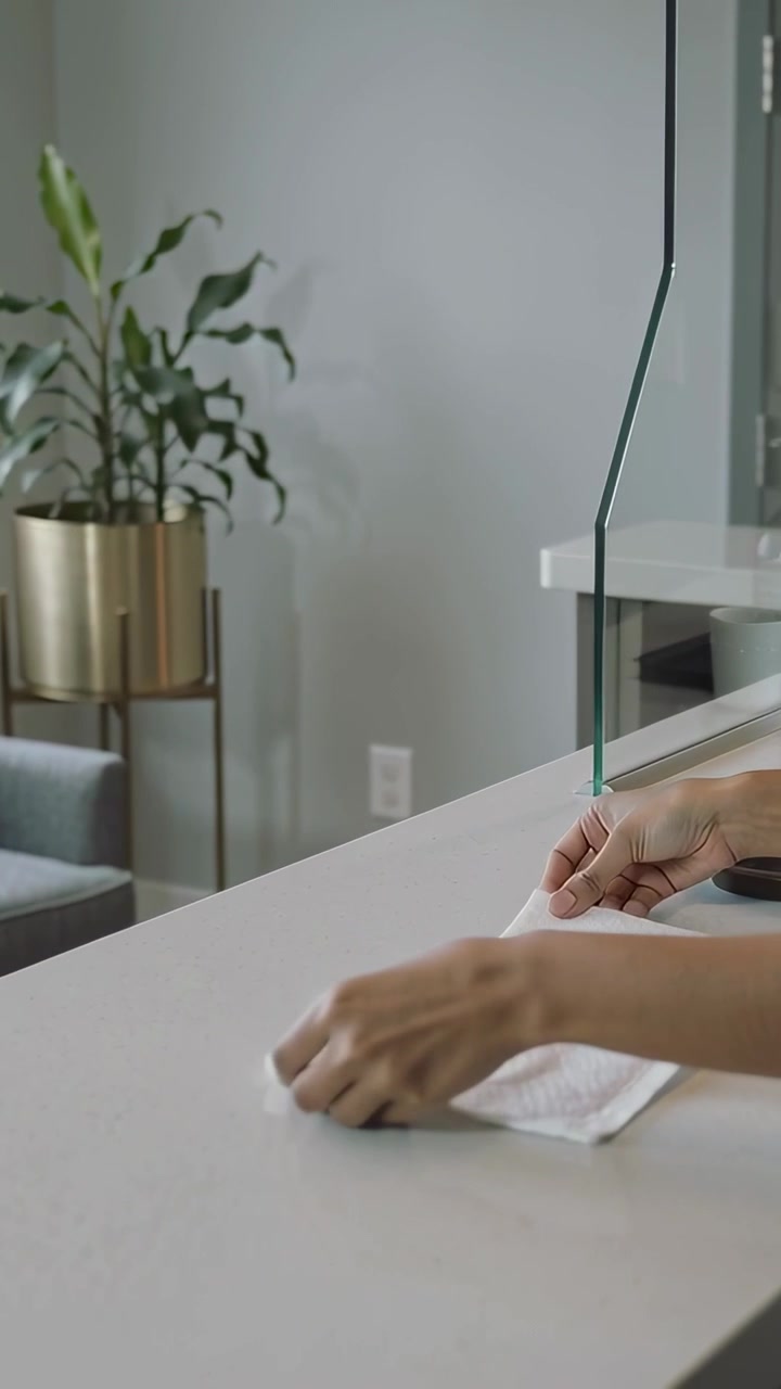 Vertical video: Placing tray, hands unfolding towel on counter near glass, short sleeves