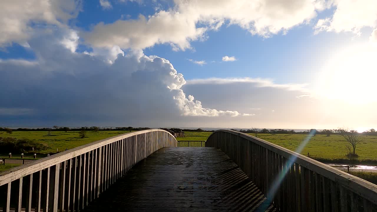 Walking on a wooden bridge with rain clouds in the distance -wide
