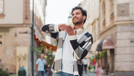 cheerful rich indian man showing wasting throwing money around hand gesture standing on city street