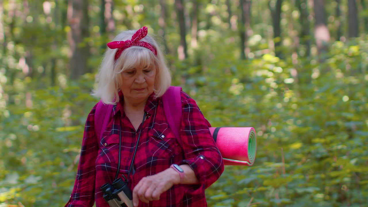 Tourist woman grandparent monitors heart rate while traveling hiking in wood, fitness activity check