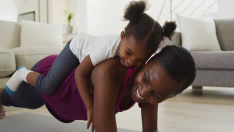 happy african american mother and daughter doing exercise at home