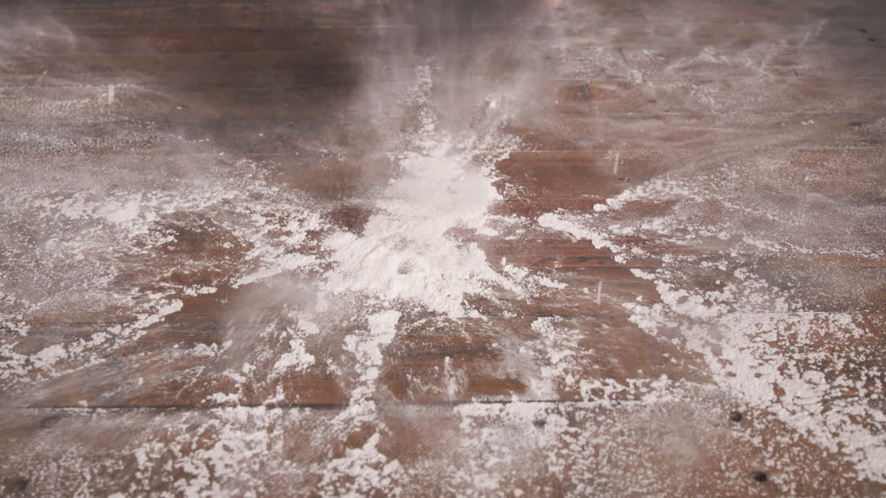 Hands going back and forth smacking a pile of flour on a table in slow motion.