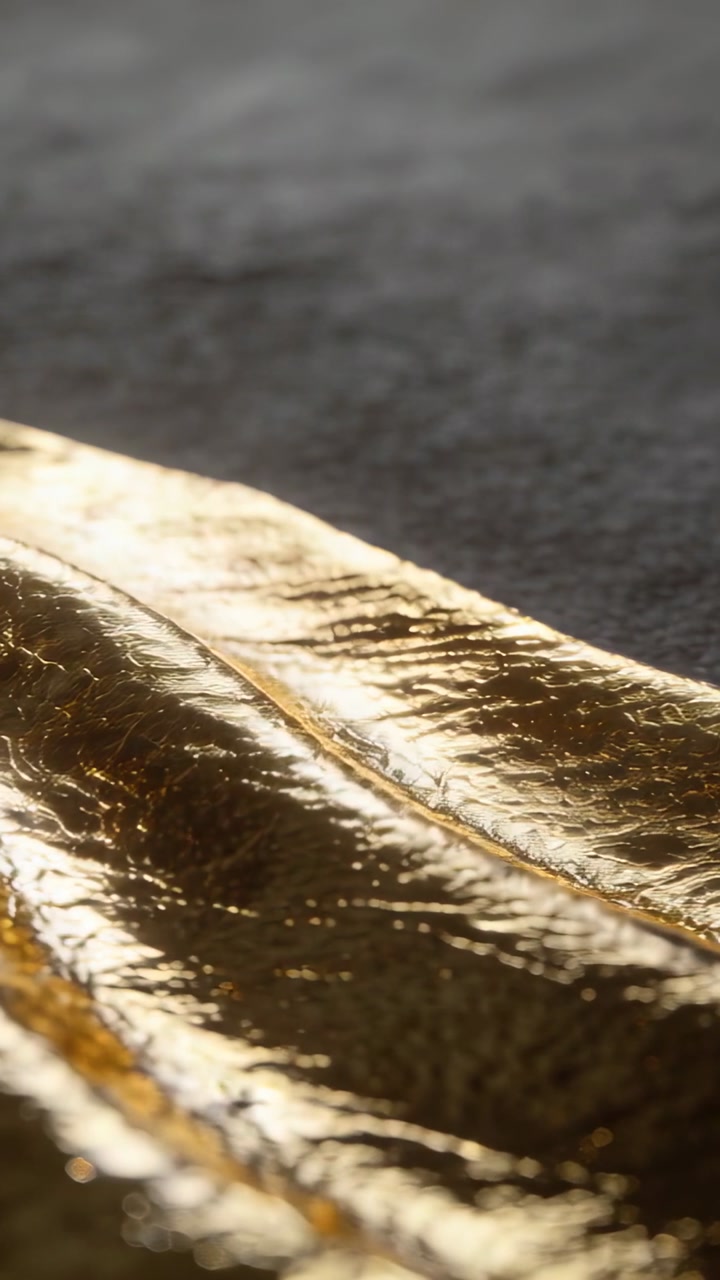 Vertical video: Sliding gold foil on studio top, showing center ridge on dark cloth as dolly moves