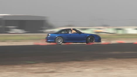 the camera follows a blue car as it glides through a drifting course at camarillo airport in camarillo california