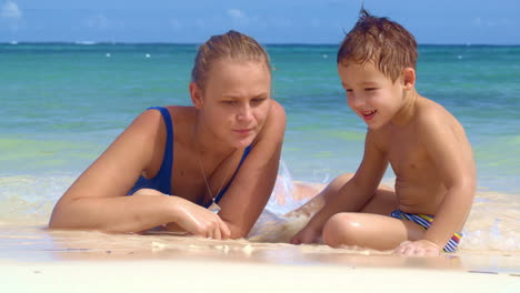 Boy-watching-mother-drawing-on-sand