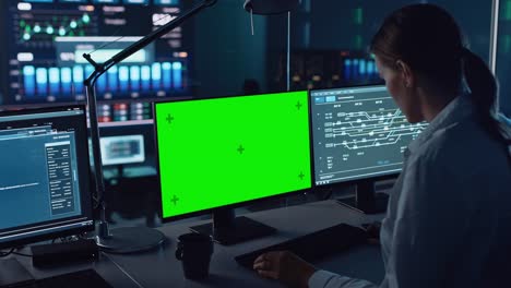 female software engineer working in a modern monitoring office with green screen mock up on a computer display. monitoring room big data scientists and managers sit in front of computers.