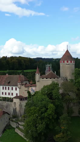 vertical, aerial: lucens castle during the day in canton of vaud, switzerland, orbit drone shot