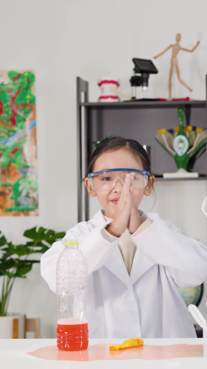 Ung studerende med sikkerhedsbriller observerer en kemisk reaktion i et eksperiment med en plastikflaske.