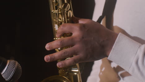 vista de cerca de las manos del hombre latino tocando el saxofón durante la actuación de música en vivo