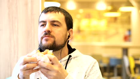 young man enjoys a delicious hamburger and listens to music.