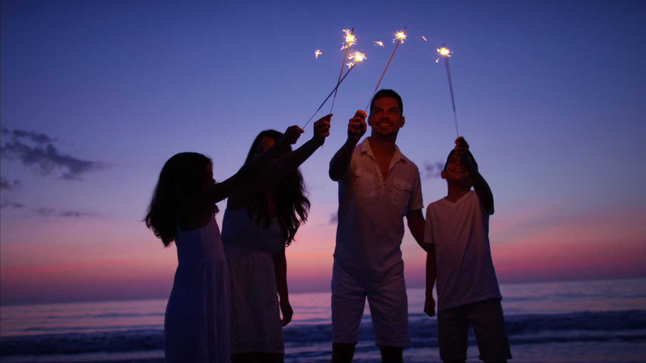 Hispanic family at sunset with sparklers on beach