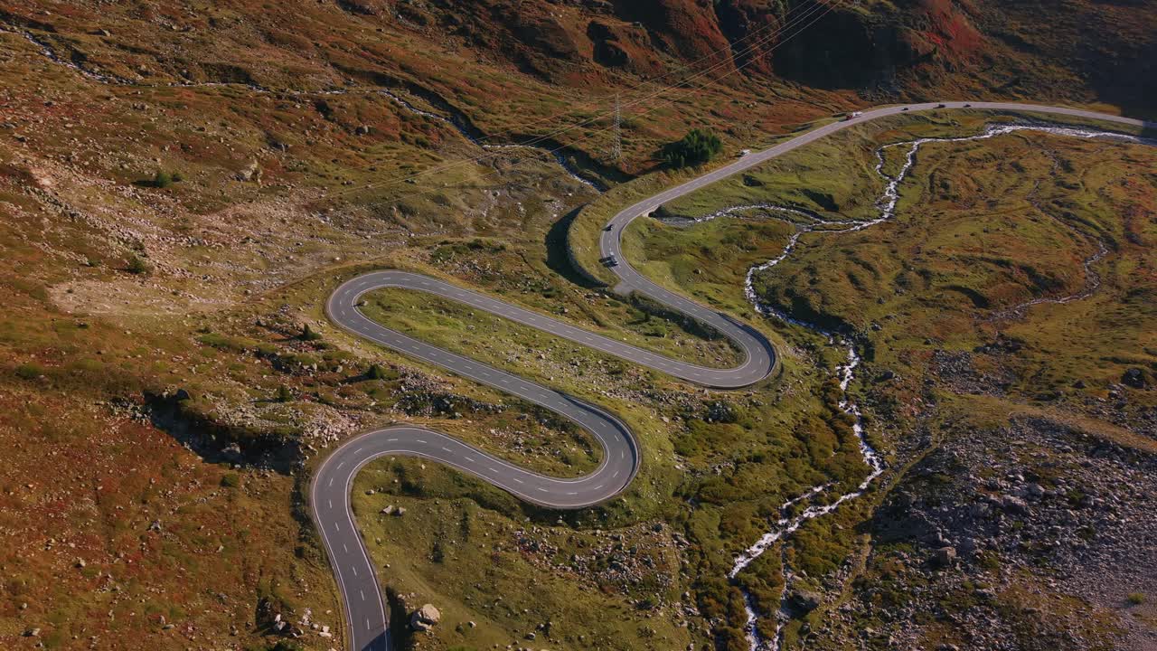 Aerial shot of the winding Julier Pass road cutting through rugged Swiss Alps with autumn colors