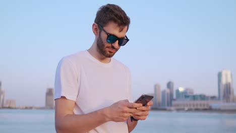 camera moves around handsome young man as he uses his phone. portrait. blurred background.