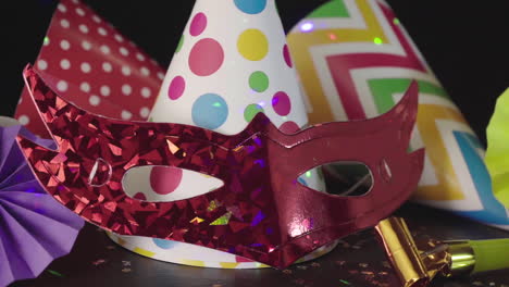 party hats, carnival mask and colorful lights on black background