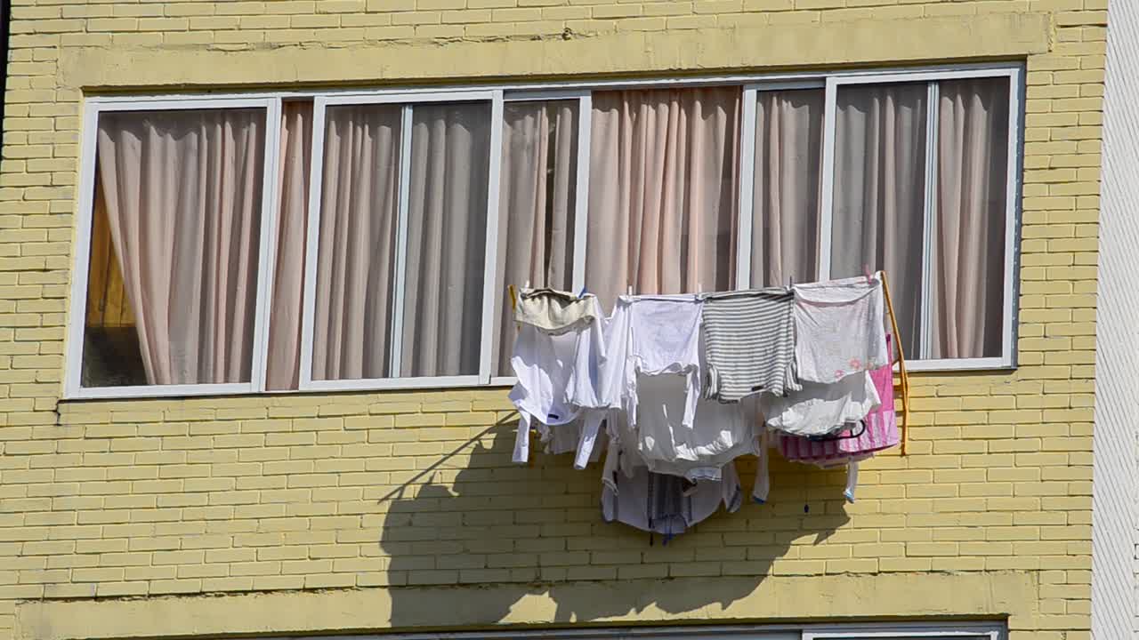 Wäsche an Leinen, ein Balkon. Wäschetrocknen im Mehrfamilienhaus.
