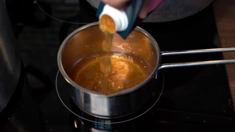 pouring collagen rich bone broth from carton to pot for heating