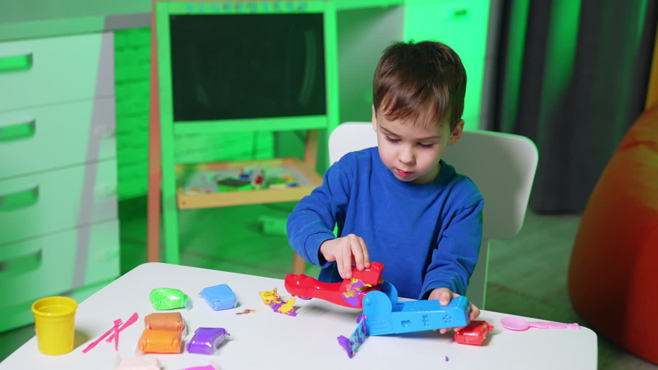 Cute Caucasian toddler cleans molding machine from plasticine. Baby boy sculptures for play dough.