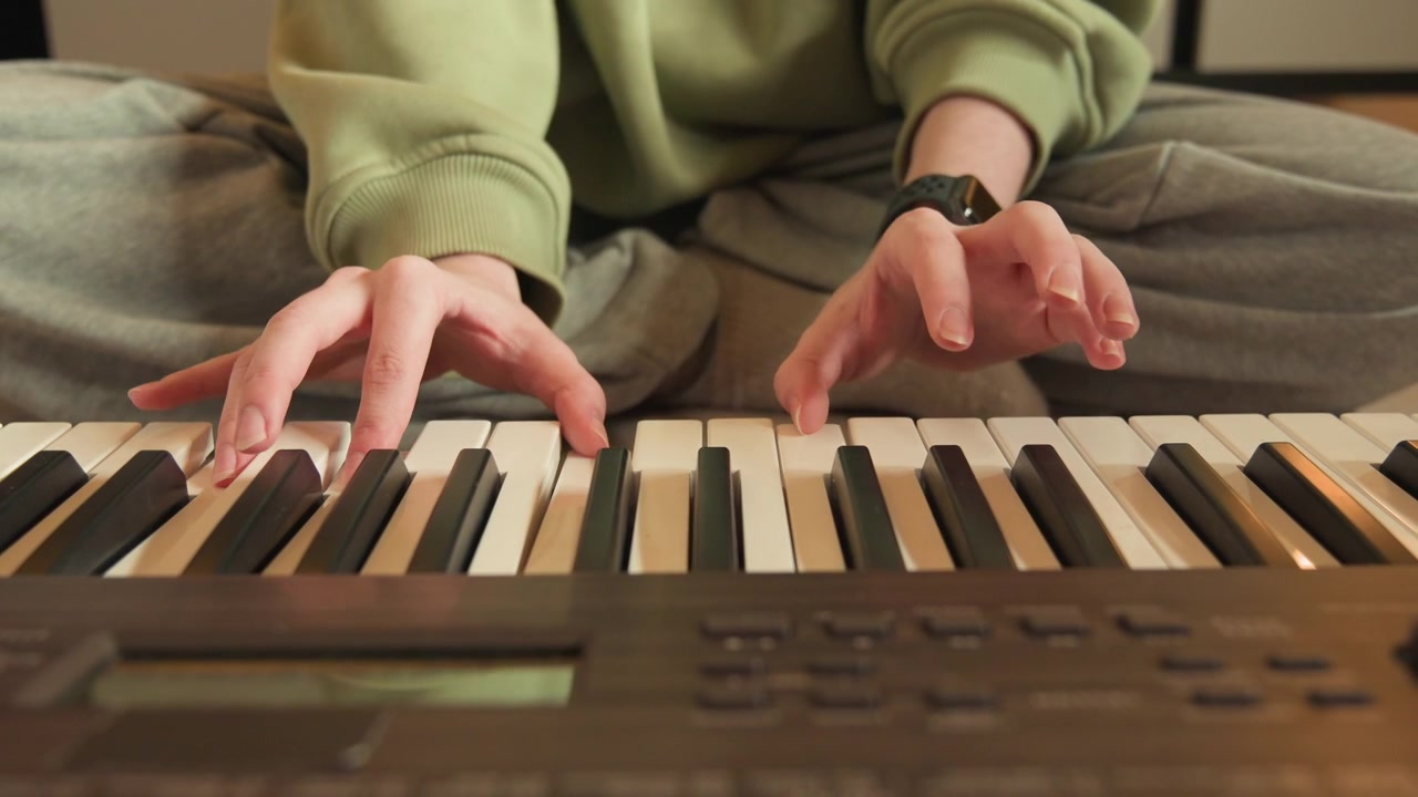Hands actively playing electronic keyboard at home, fingers pressing keys with smooth movement and slight blur, creating sense of practice, rhythm, concentration, and gentle musical expression