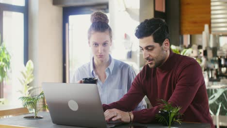 pareja trabajando en una computadora portátil en un café