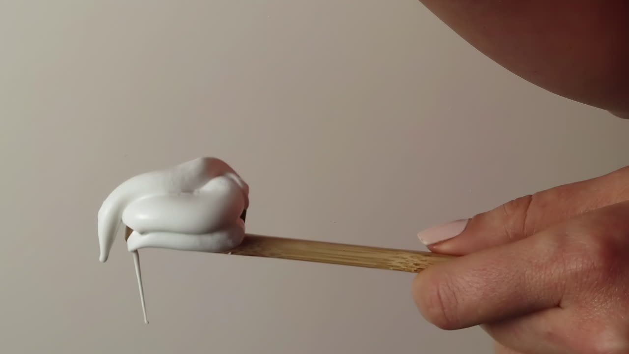 Close up of a woman pouring a big amount of toothpaste on a toothbrush