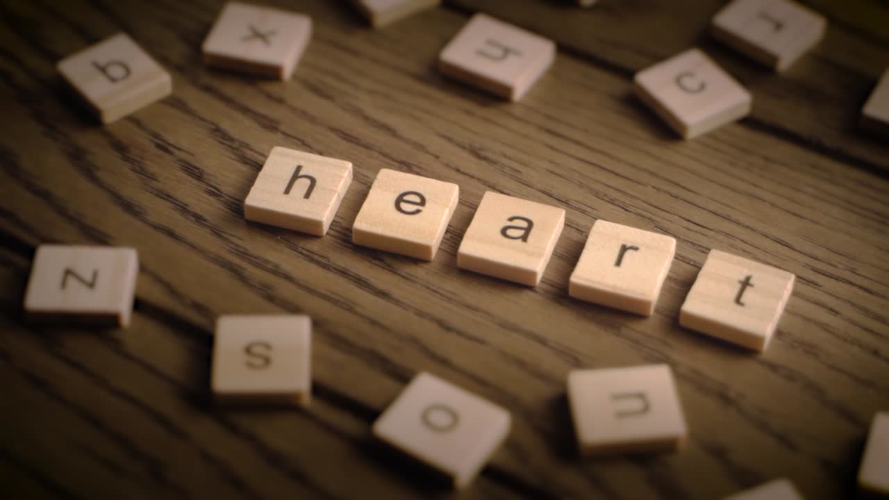 Wooden tiles spell out heart as the camera pans smoothly over a rustic wooden surface with warm lighting.