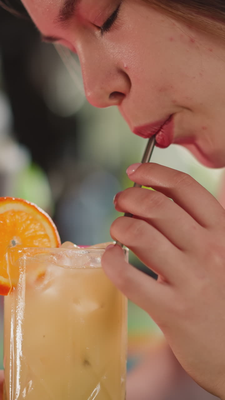 una mujer atractiva bebe un cóctel a través de paja en un bar. una mujer seductora se refresca con una bebida alcohólica exótica descansando en un club nocturno.