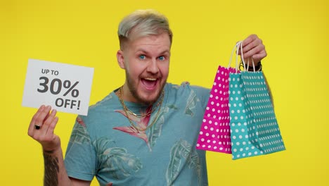 cheerful tourist man showing shopping bags and up to 30 percent off inscriptions banner black friday