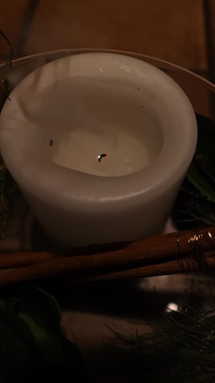 Cette courte vidéo verticale montre une flamme de bougie s’éteignant doucement en intérieur.
