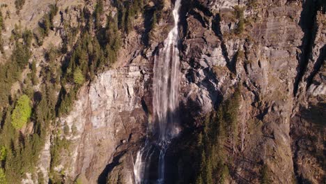 drohnenaufnahmen aus der luft, die einen atemberaubenden wasserfall in grindelwald in den schweizer alpen hinuntersteigen