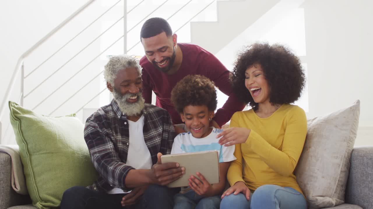 Multi-generation family laughing while using digital tablet at home