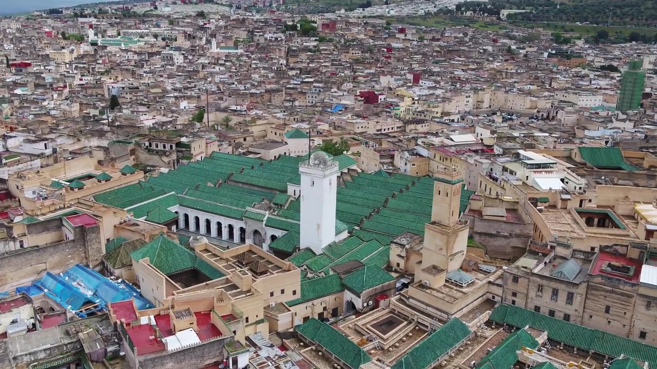 Vista aérea con dron de los minaretes y tejados verdes de la Mezquita Al Quaraouiyine, rodeada por la densa e histórica Medina de Fez en Marruecos, ideal para proyectos culturales.