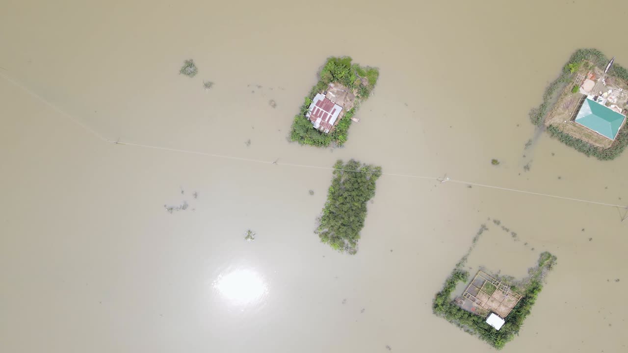 Aerial top view of house submerged in flood water with power lines and trees in Bangladesh, South Asia - Sylhet