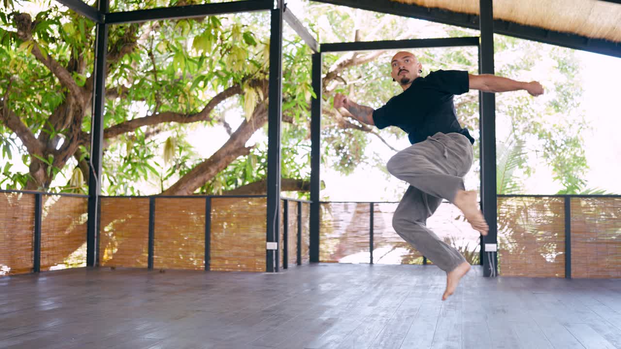 Uomo che pratica arti marziali dinamiche e movimenti di danza in uno studio all'aperto