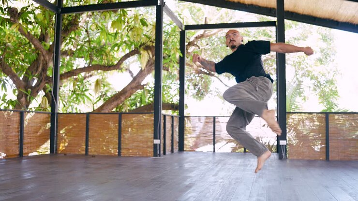 Uomo che pratica arti marziali dinamiche e movimenti di danza in uno studio all'aperto
