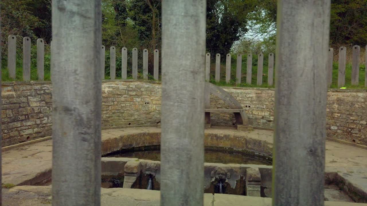 A tracking shot from the outside of a holy well in the English countryside