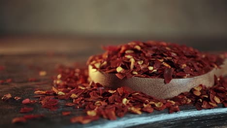 Flocken-Roter-Chilischote-In-Holzlöffel-Nahaufnahme-Auf-Einem-Küchentisch.