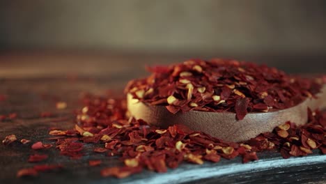 copos de pimienta roja caliente en una cuchara de madera en primer plano en una mesa de la cocina.