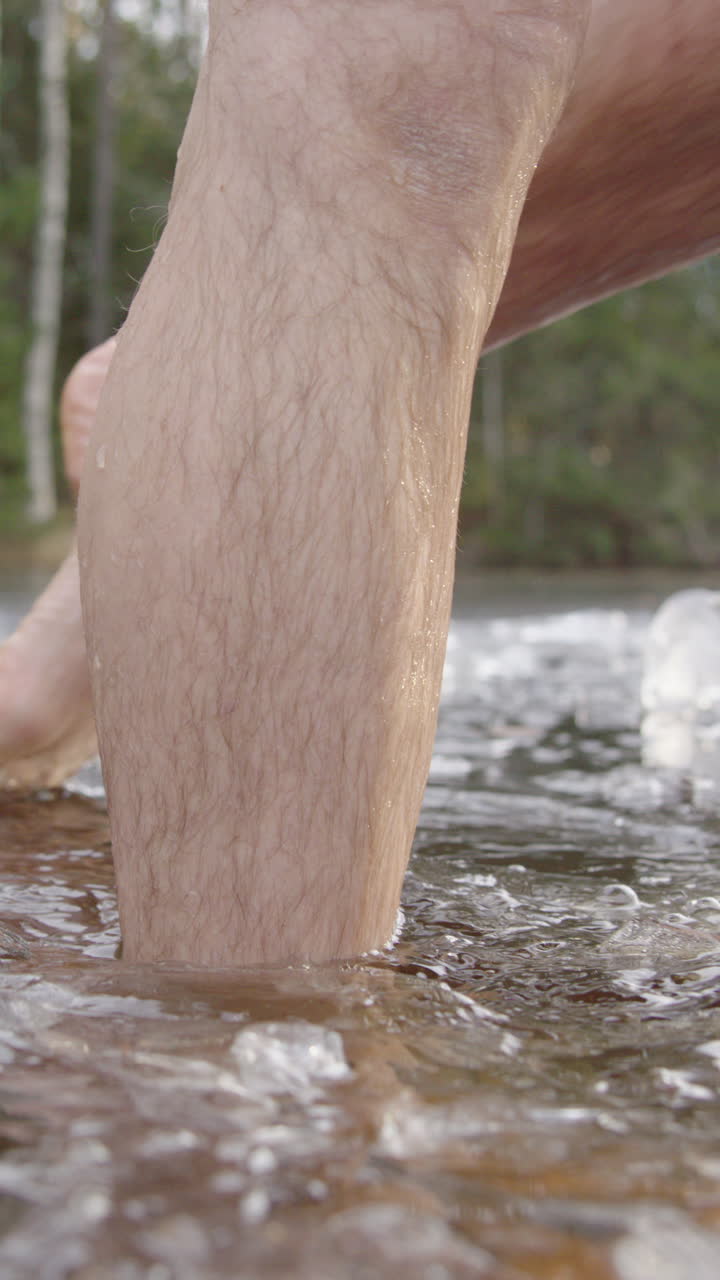 An ice bathers legs as he exits the frozen lake, vertical
