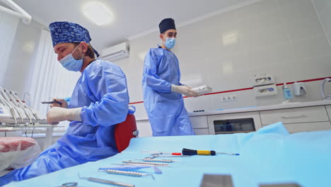 dentist is preparing tools for tooth treatment. assistant gives the doctor sterile instruments at the dental clinic. teamwork of doctors. health care concept.