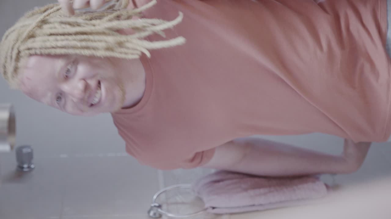 A person with albinism and dreadlocks in a bathroom