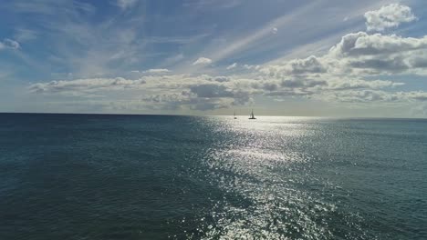 plataforma rodante aérea, silueta de veleros en el océano pacífico, reflejo de la luz del sol en la superficie del agua