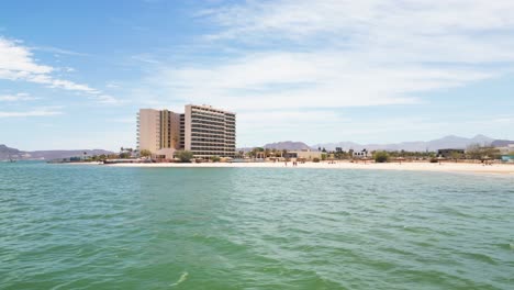 tall beachfront hotel with calm turquoise water at playa posada, la paz, mexico