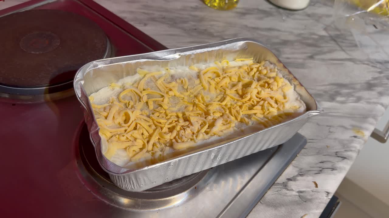 Lasagne w aluminiowej misce, gotowa do podgrzania.