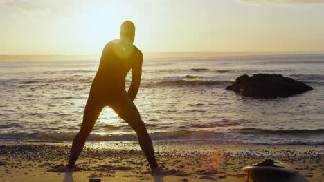rear view of mid-adult caucasian male surfer stretching and warming up before surfing at beach 4k