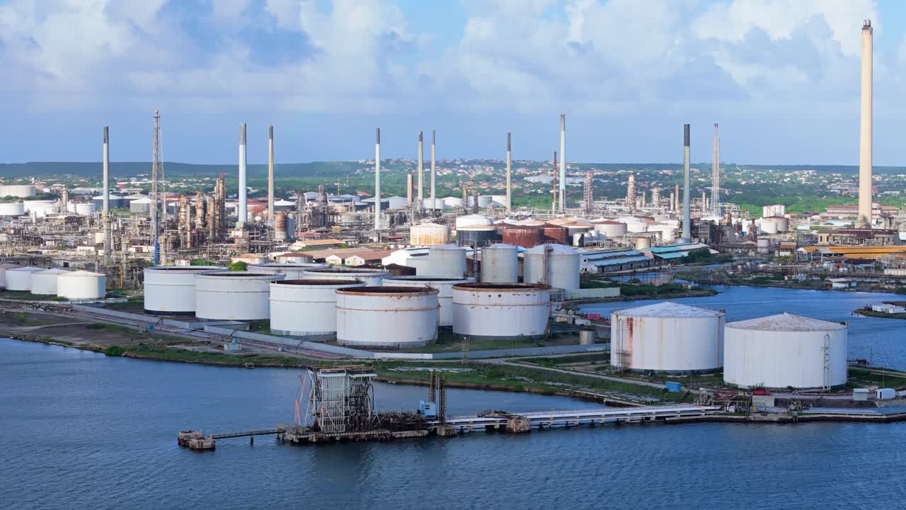 해안 열대 섬의 석유 정제소 스택과 저장 크가 구름 그림자로 여 있습니다.