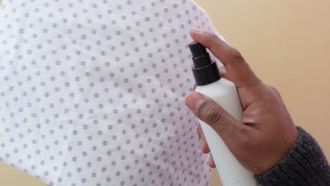 close up of a hand spraying a white fabric with a spray bottle